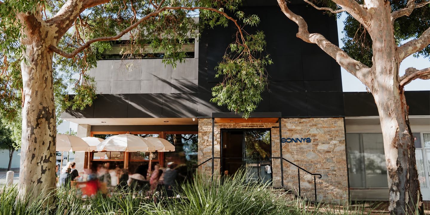 The front of Sonny's on Hobart Street: umbrella tables busy under the gum trees, with the stone frontage and the blue Sonny's sign beside the entrance.